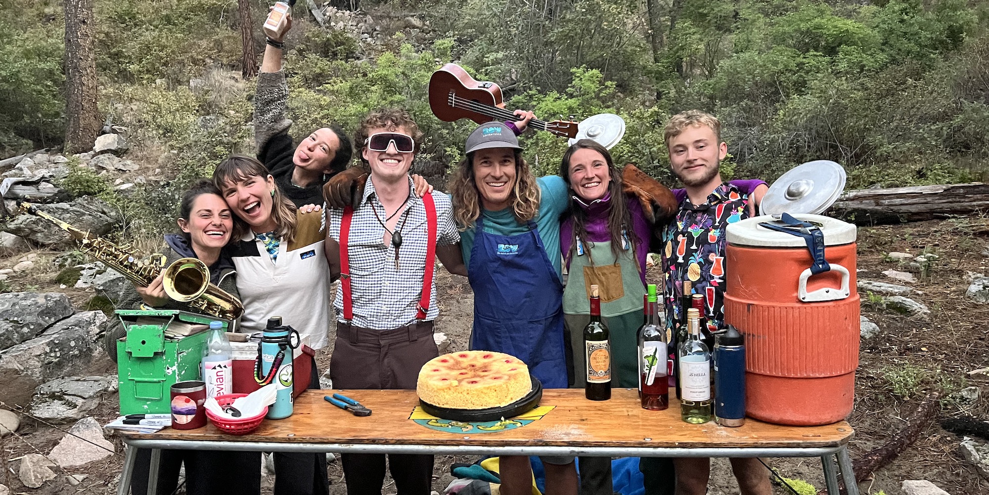 ROW Adventures river guides standing behind the camp kitchen table with a pineapple upside down cake smiling for a photo