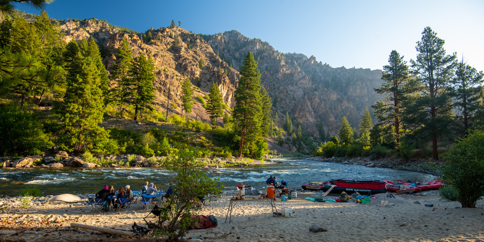 Campsite along the Middle Fork Salmon River full of people and gear sprawled out