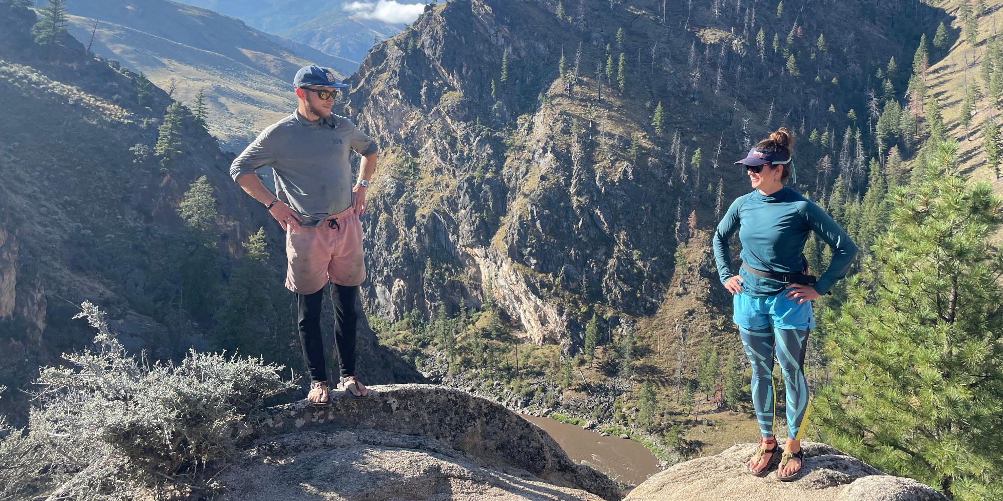 two people on rocky mountain above river