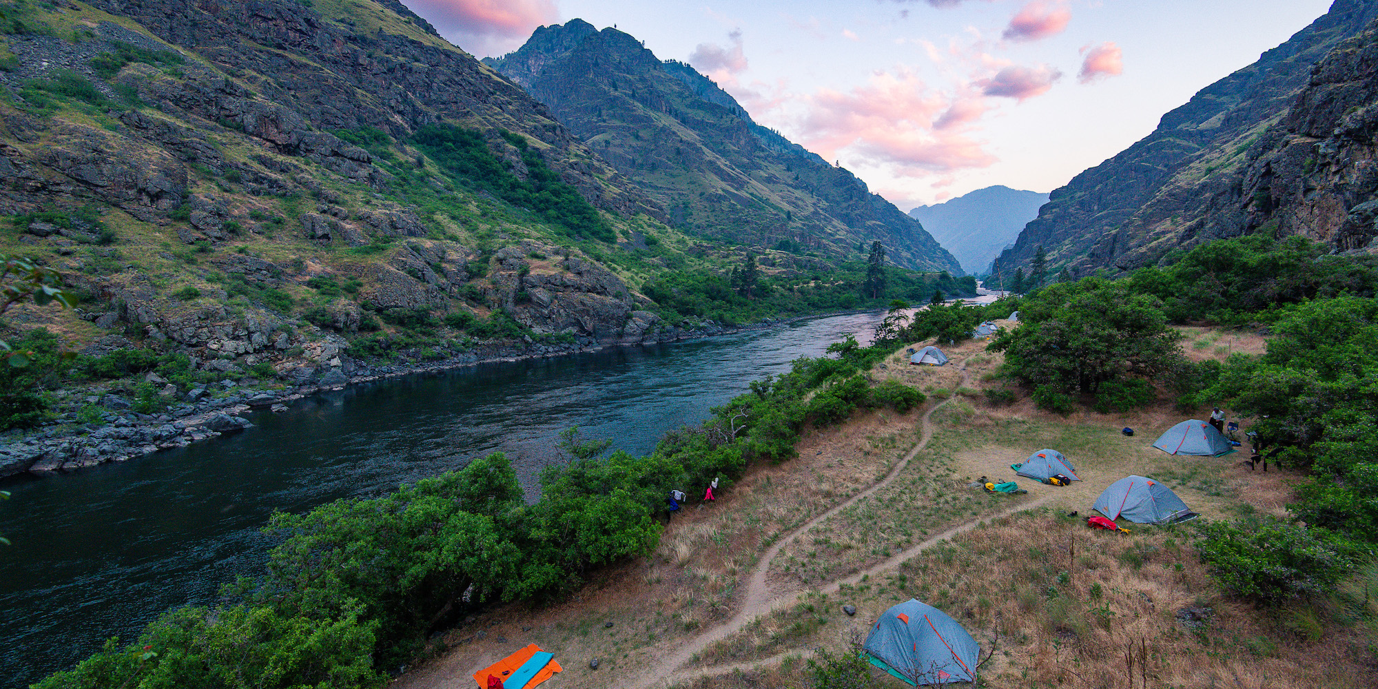 Tents set up at a campsite along the Snake River at sunset